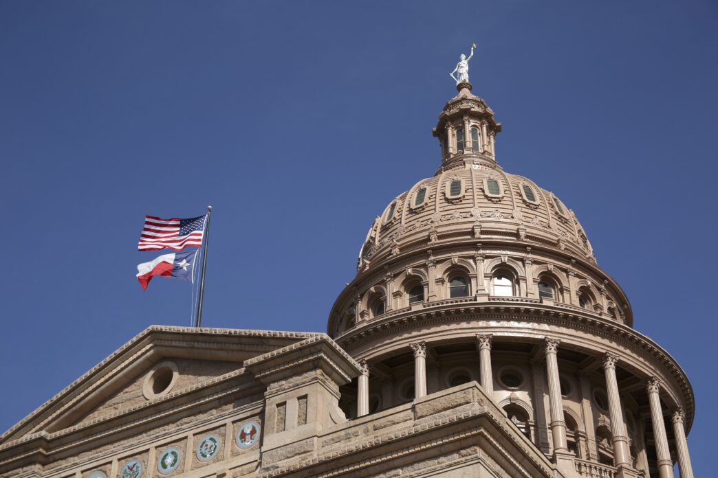 The Texas Capitol dome with U.S. and Texas flags blowing in the breeze.