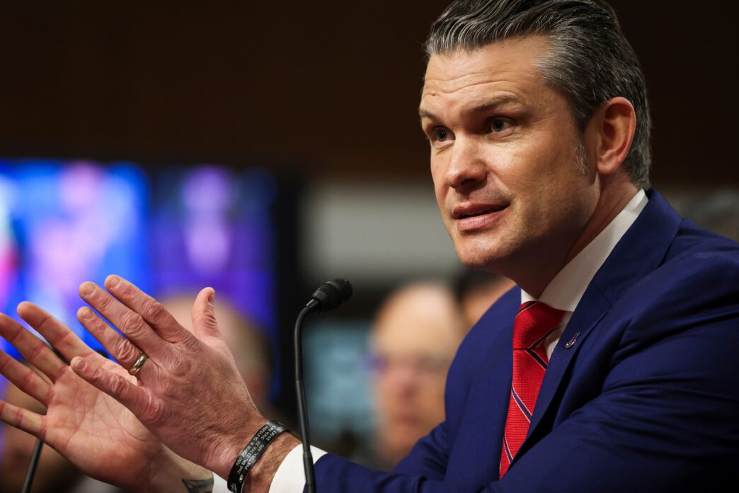 U.S. Secretary of Defense Pete Hegseth speaking into a microphone in a formal setting.