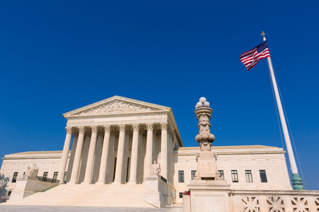 The United States Supreme Court building with an American flag in the foreground.
