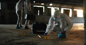 CSI team in hazmat suits collects DNA evidence at an abandoned warehouse crime scene.