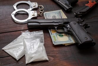 Handcuffs, pistol, cocaine packets, and US dollars depict drugs and illegal business concept.