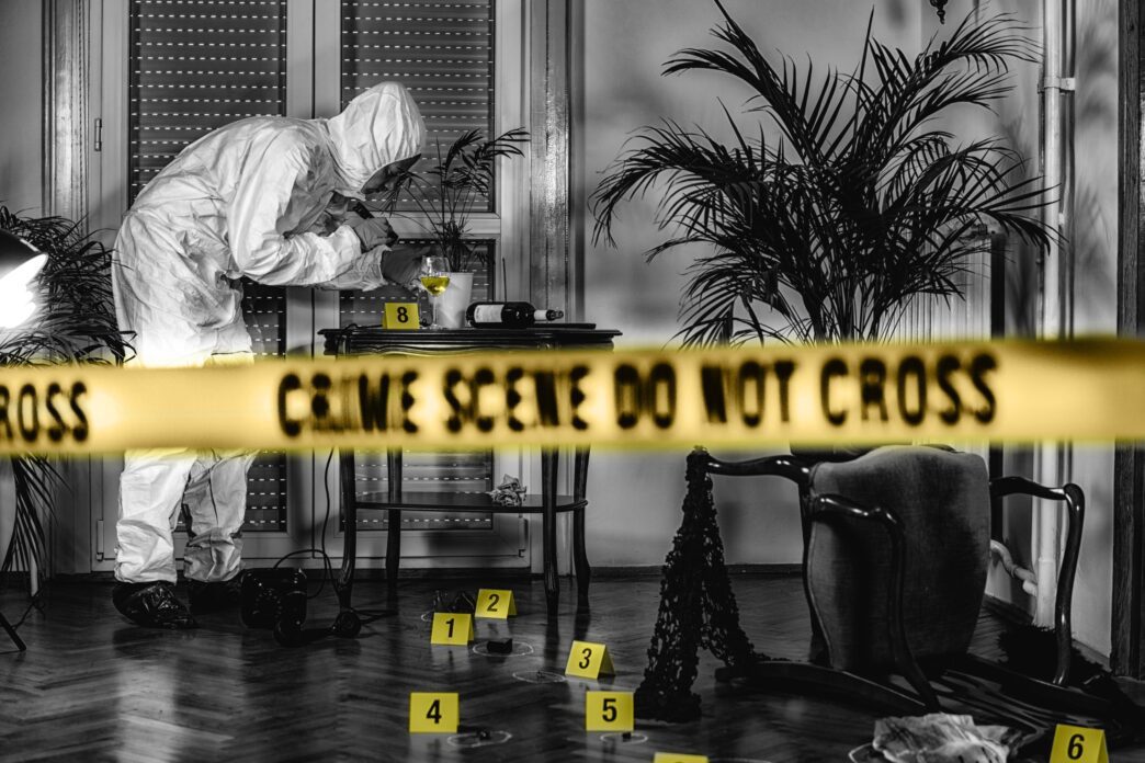 Forensics expert in protective gear collecting clues at a crime scene with evidence markers.
