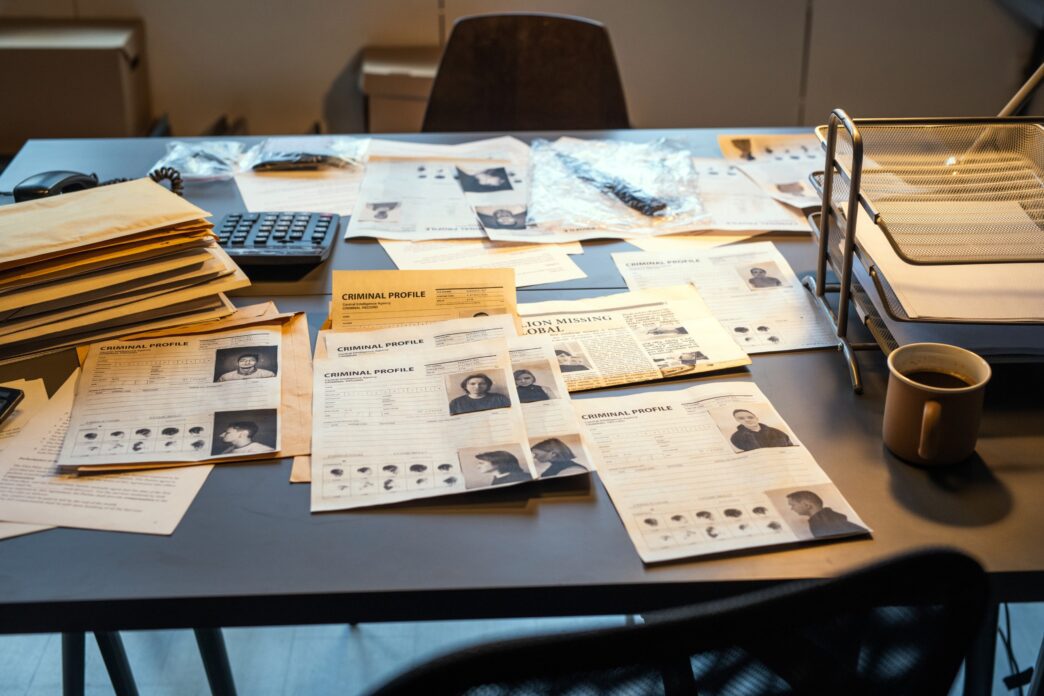FBI agent's workplace with criminal profiles, evidence, and clues scattered on the desk.