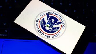 The U.S. Department of Homeland Security logo displayed on a smartphone screen over a keyboard.