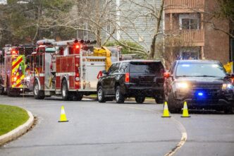 Police cars and fire trucks with bright lights are lined up on the street.