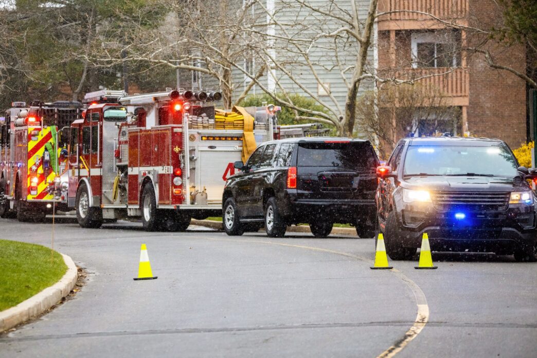 Police cars and fire trucks with bright lights are lined up on the street.