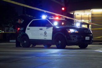 Police car and yellow tape block street at night after shooting; credit Elliott Cowand Jr-Shutterstock.