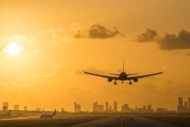 At sunrise, an airplane descends for a landing at Miami International Airport, with the Miami Downtown skyline forming a stunning backdrop