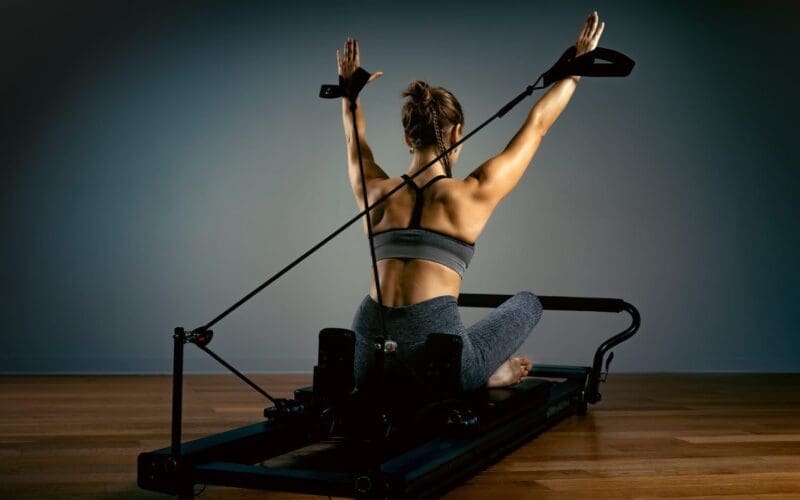 Young girl doing Pilates exercises with a reformer couch